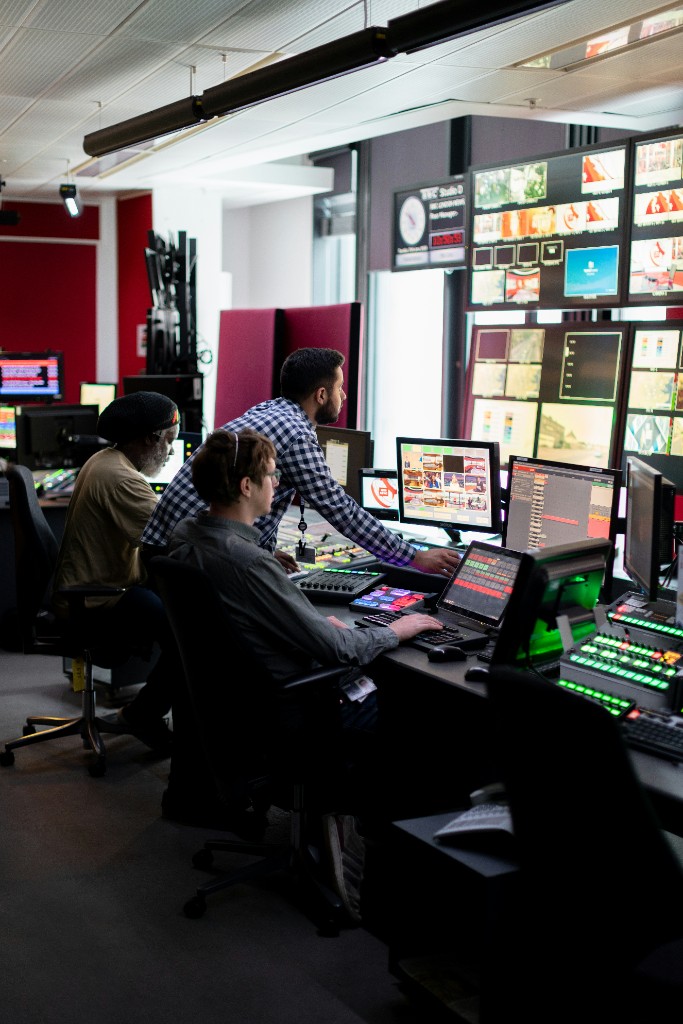 Production team collaborating at a multi-monitor control console